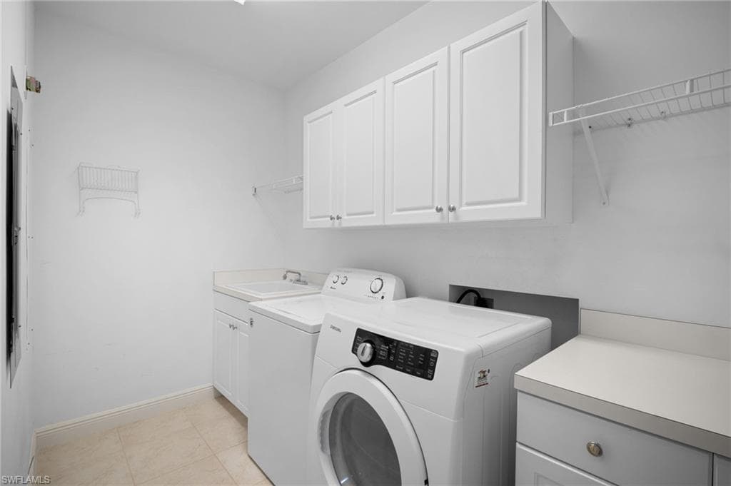 Laundry room with cabinet space, light tile patterned floors, and washing machine and dryer