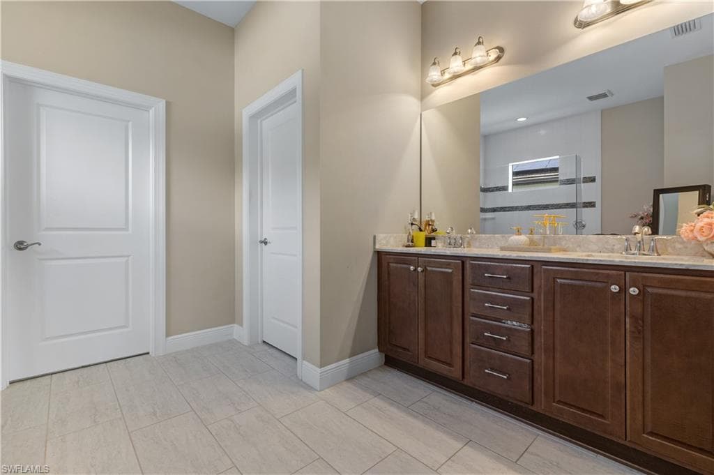 Full bathroom with double vanity and baseboards