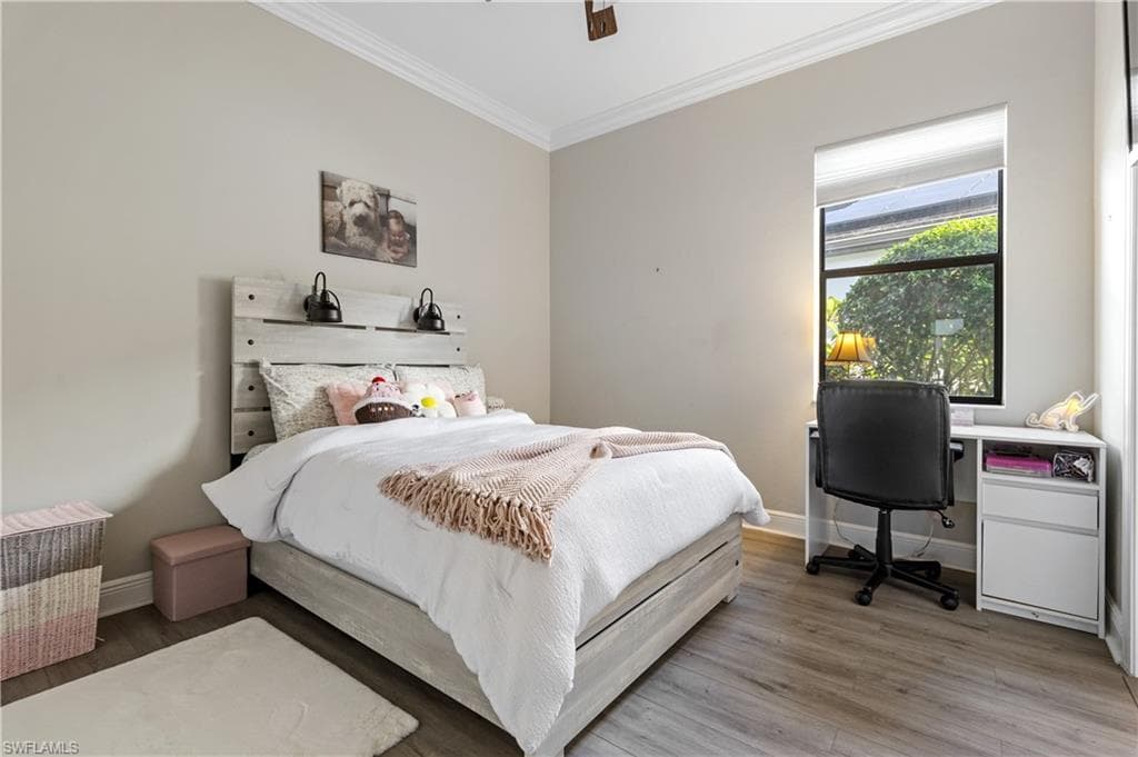 Bedroom with ornamental molding, wood finished floors, an office area, and a ceiling fan