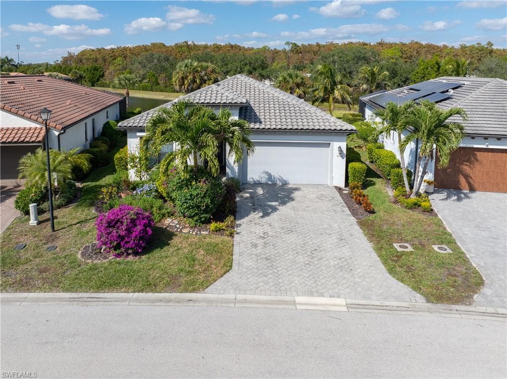 View of front of house with a tile roof, stucco siding, decorative driveway, and a garage