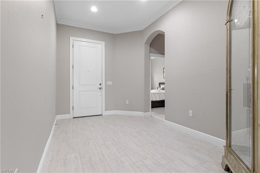 Unfurnished room with crown molding, arched walkways, recessed lighting, and wood tiled floors