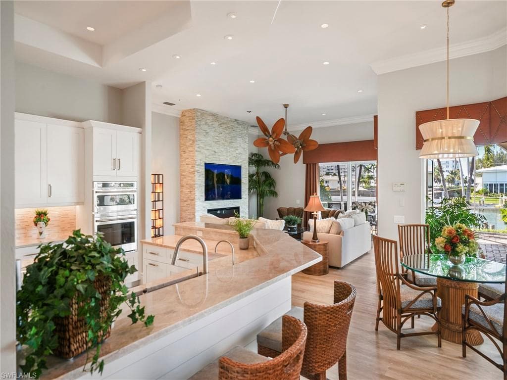 Kitchen with white cabinetry, light wood-style flooring, light stone counters, recessed lighting, and a stone fireplace