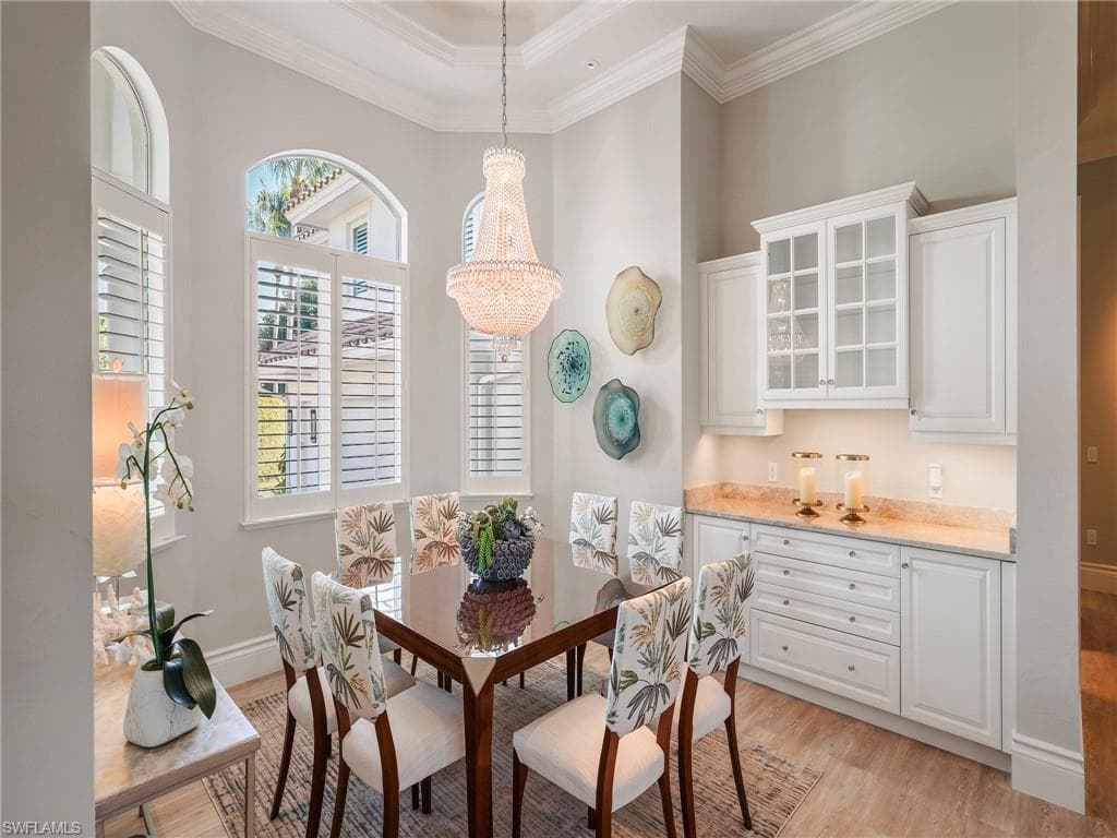 Dining space with ornamental molding, light wood-style floors, and a chandelier