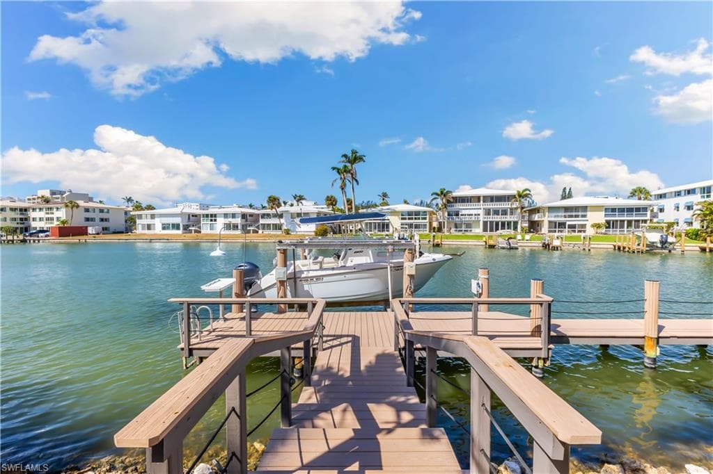 Dock area with a water view, boat lift, and a residential view