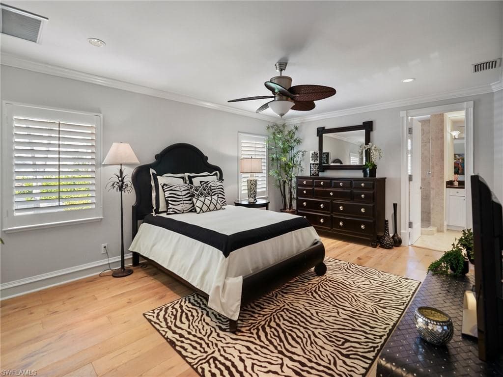 Bedroom featuring light wood-type flooring, ornamental molding, and a ceiling fan
