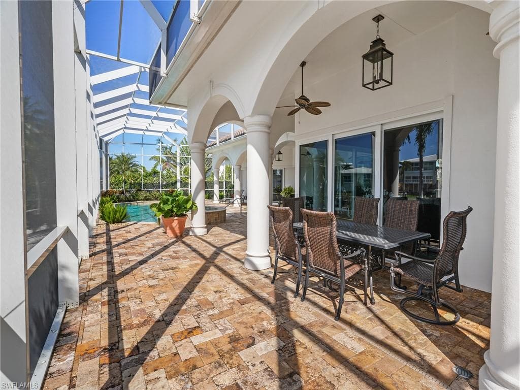 View of patio / terrace featuring a sunroom, a ceiling fan, outdoor dining space, a lanai, and an outdoor pool