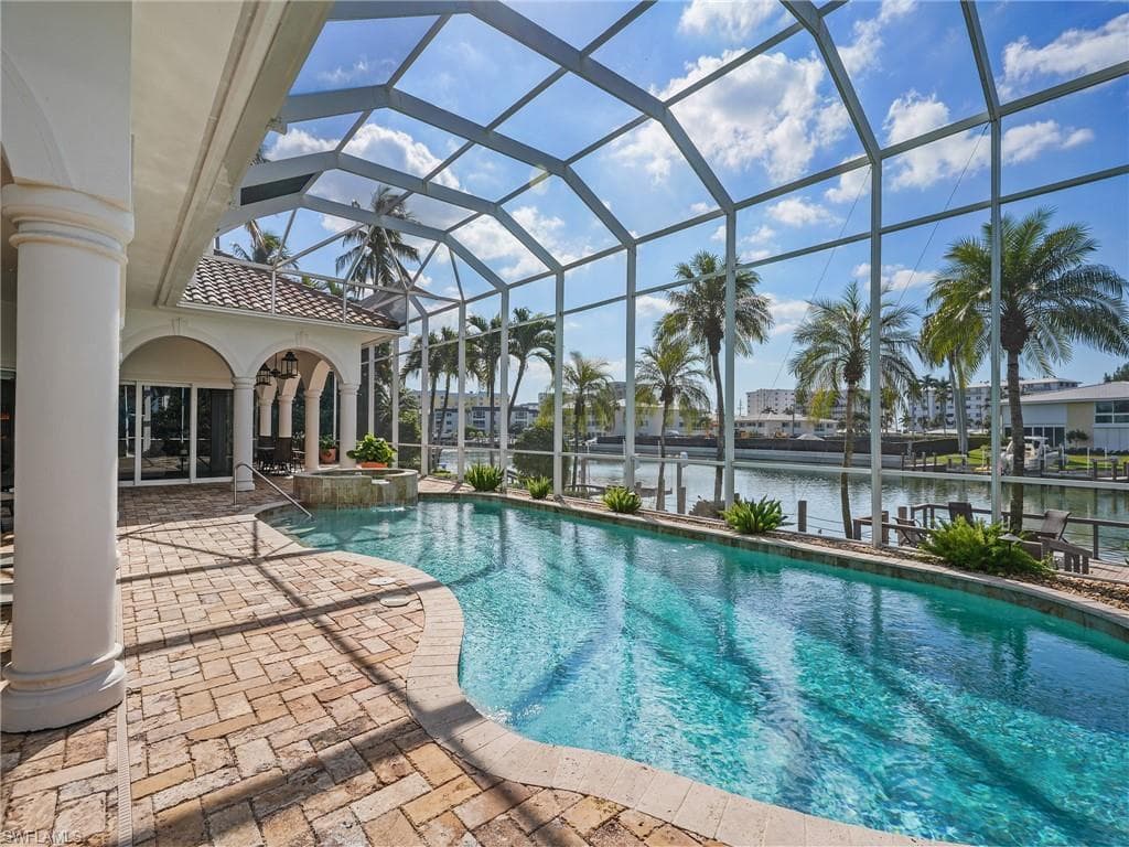 View of pool with a patio area, a water view, a sunroom, a lanai, and a pool with connected hot tub