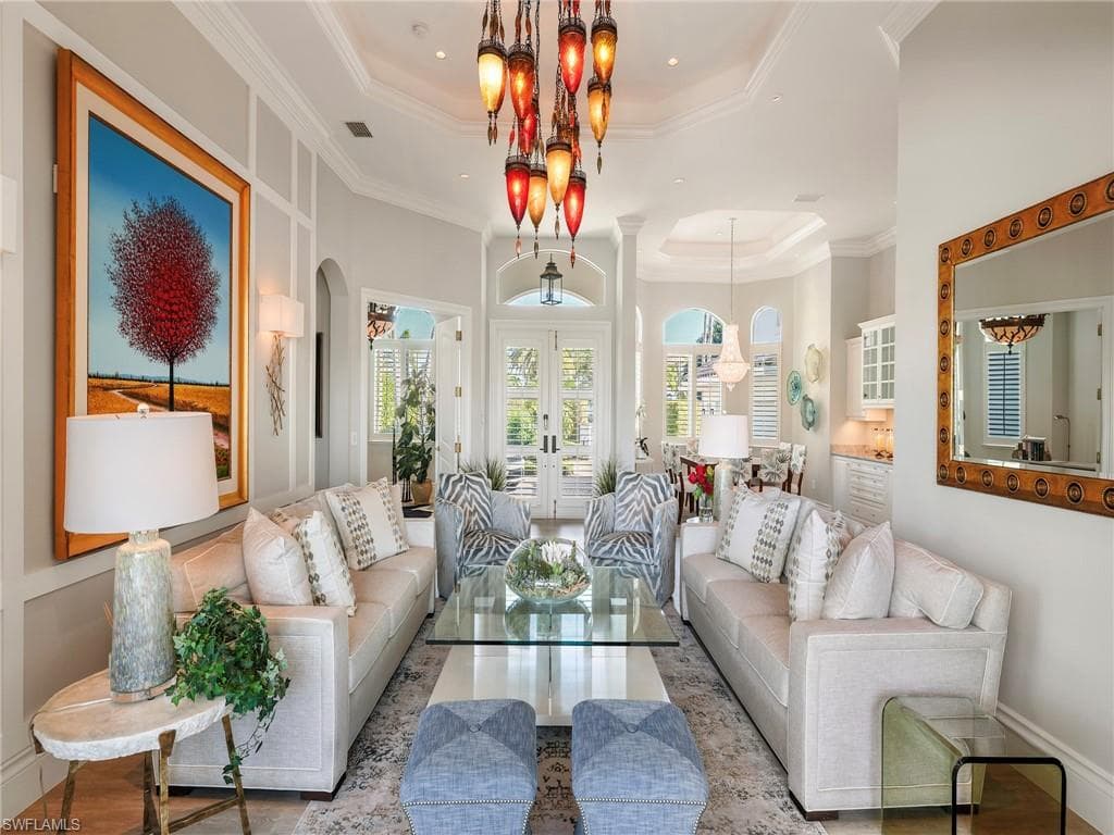 Living area with a raised ceiling, french doors, arched walkways, crown molding, and wood finished floors