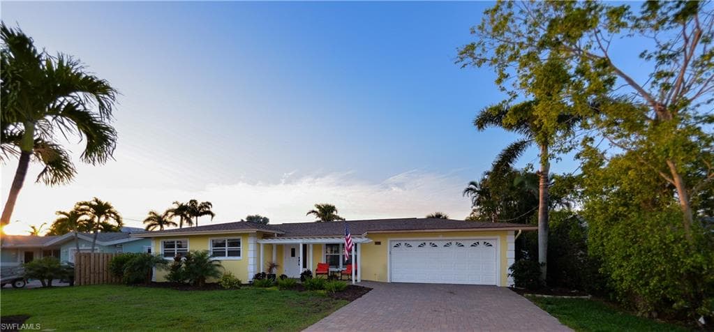 Single story home featuring a lawn and a garage