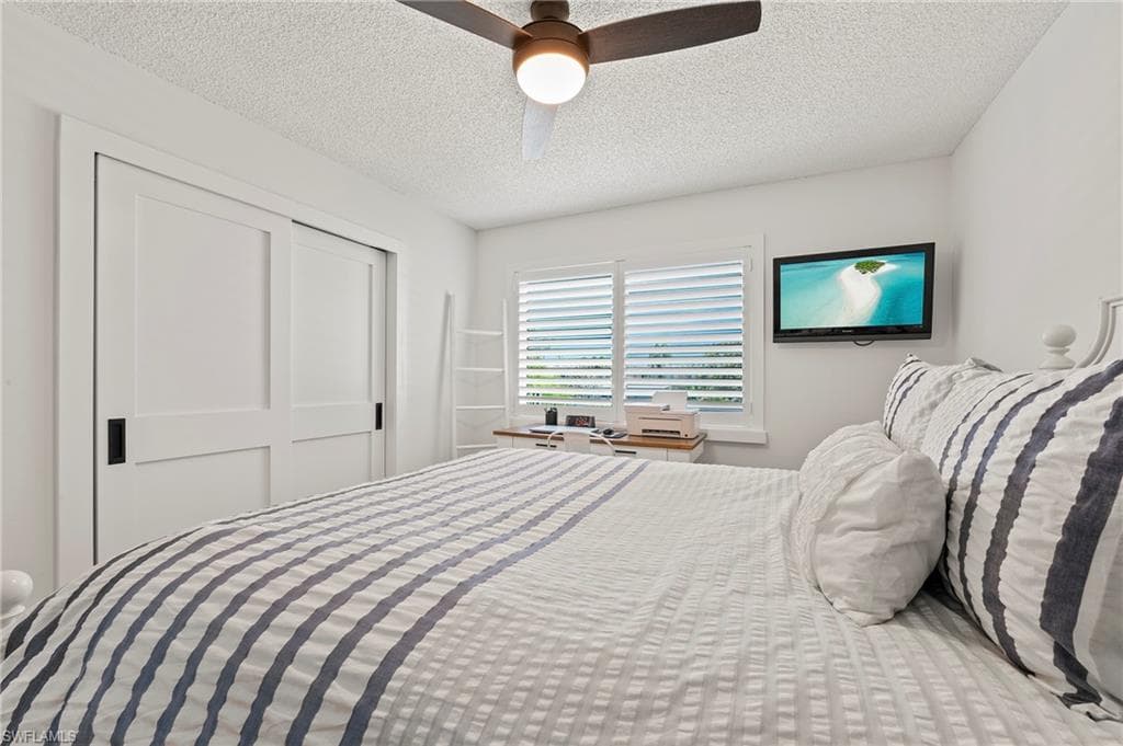 Bedroom featuring a textured ceiling, ceiling fan, and a closet