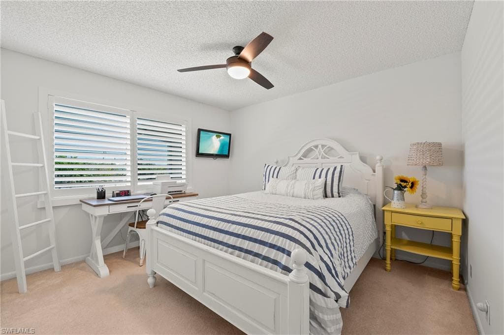 Bedroom featuring light carpet, a ceiling fan, and a textured ceiling