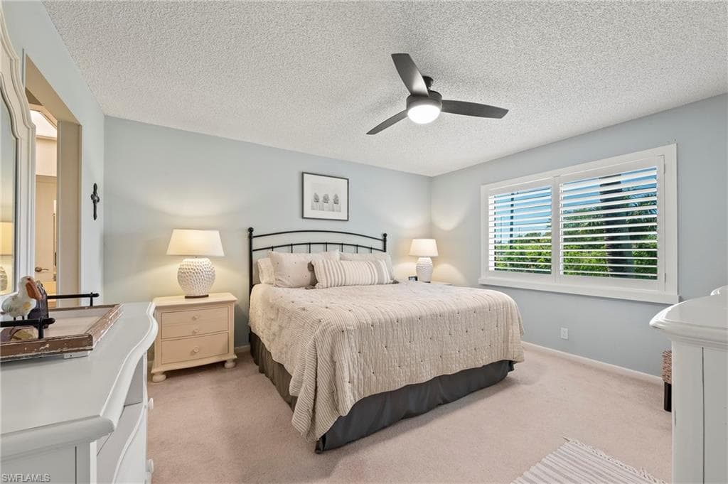 Bedroom with light colored carpet, a ceiling fan, and a textured ceiling