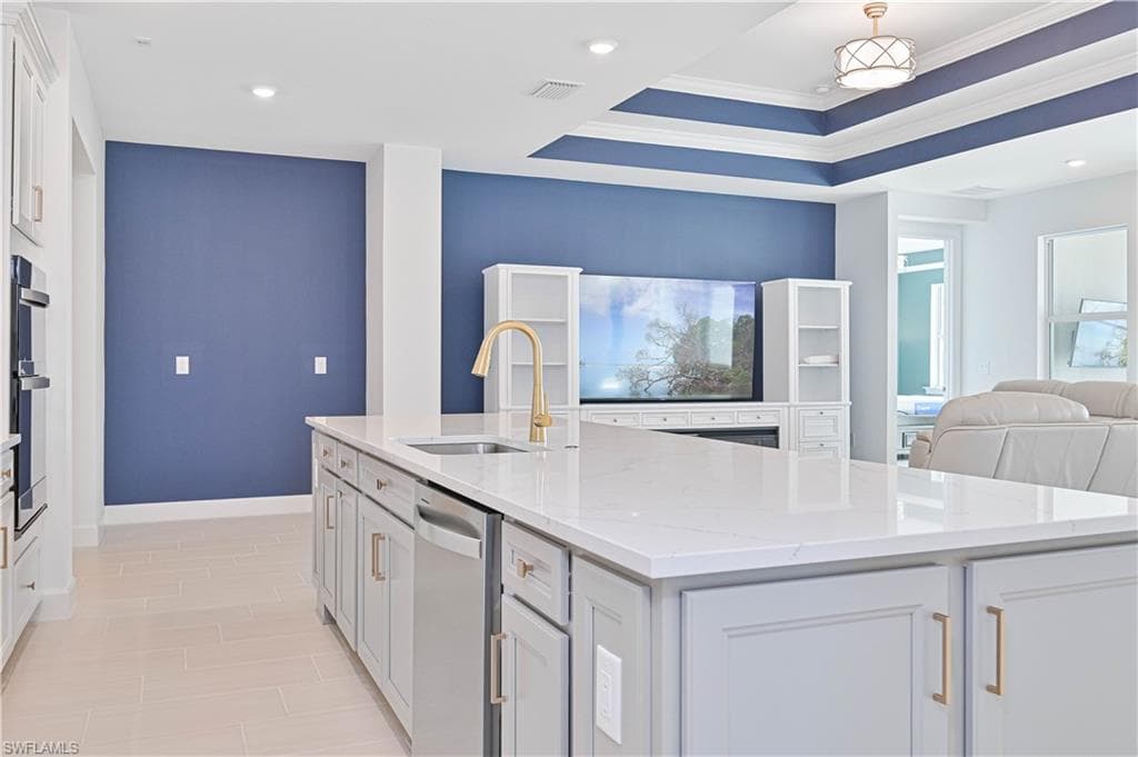 Kitchen featuring light stone counters, open floor plan, white cabinetry, a kitchen island with sink, and recessed lighting
