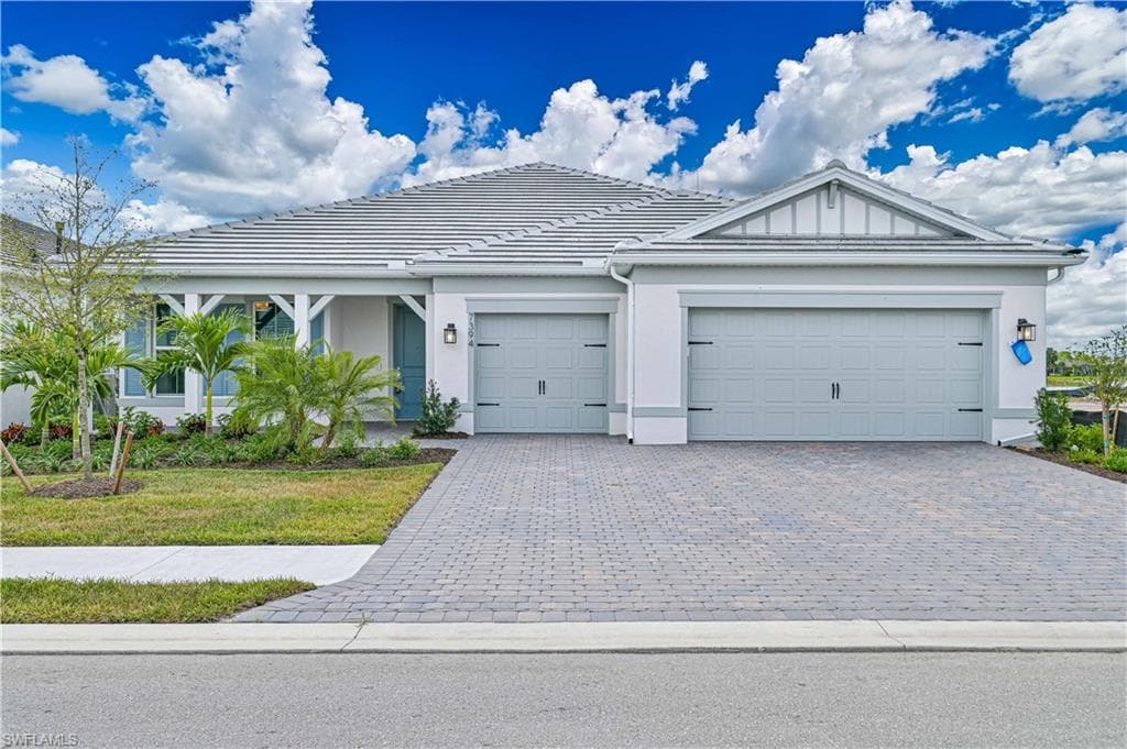 Ranch-style home featuring a garage, decorative driveway, a tile roof, and stucco siding