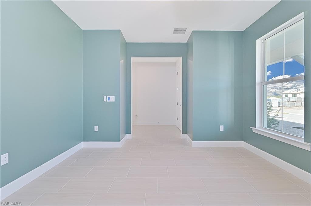 Empty room featuring baseboards and light tile patterned floors