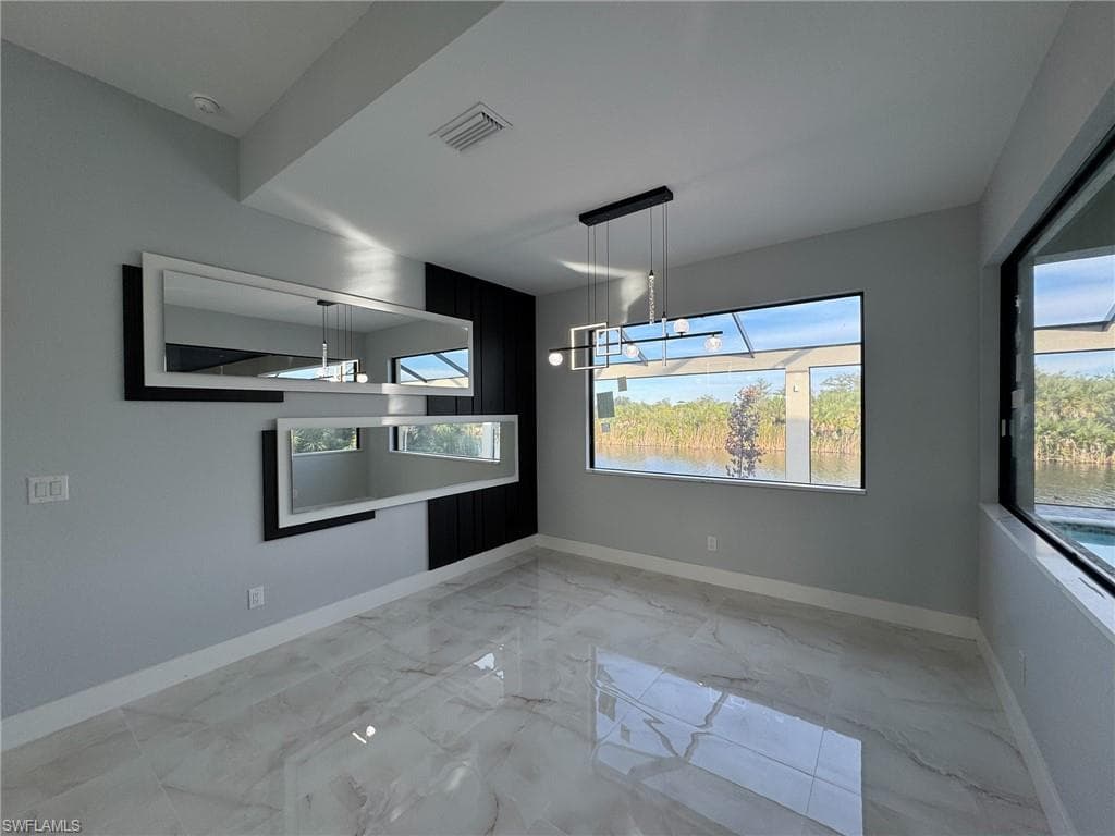 Unfurnished dining area with light marble finish flooring and baseboards