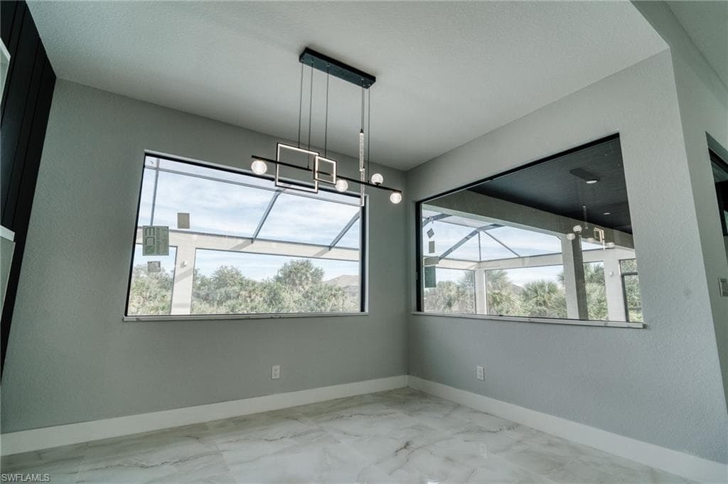 Unfurnished dining area with baseboards and light marble finish flooring