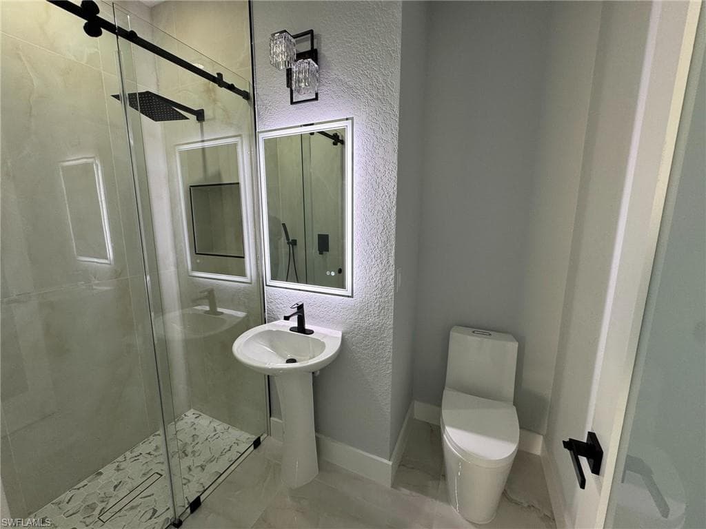 Full bathroom featuring a textured wall, a stall shower, and marble finish floors