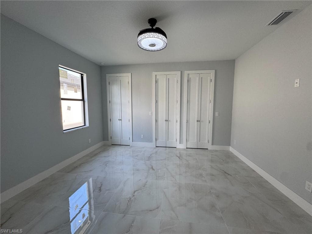 Unfurnished bedroom with multiple closets and light marble finish flooring