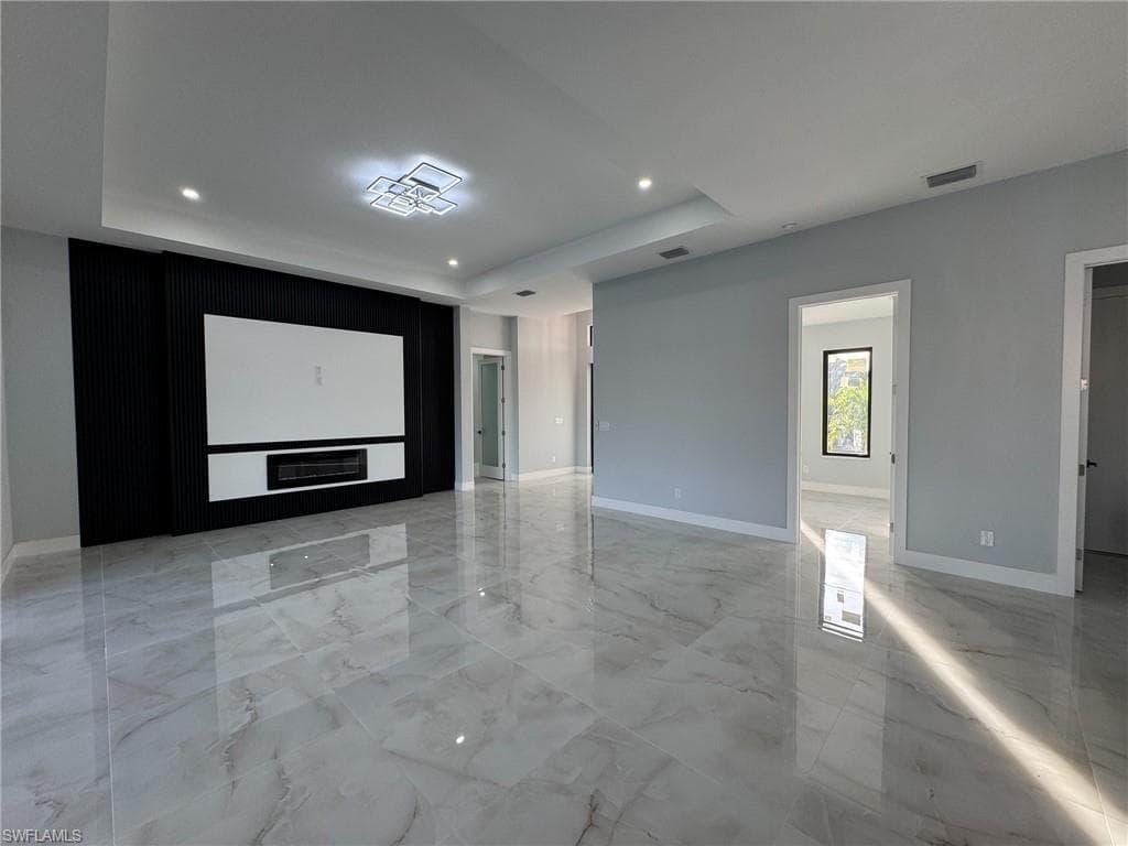 Spare room with light marble finish flooring, a raised ceiling, and recessed lighting