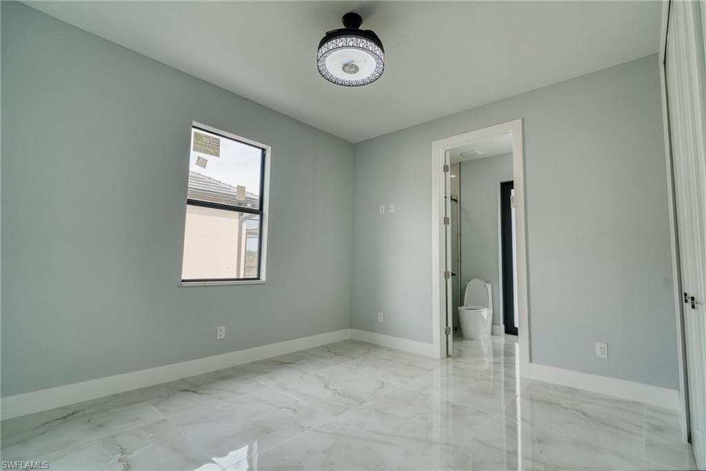 Unfurnished bedroom featuring light marble finish floors and baseboards