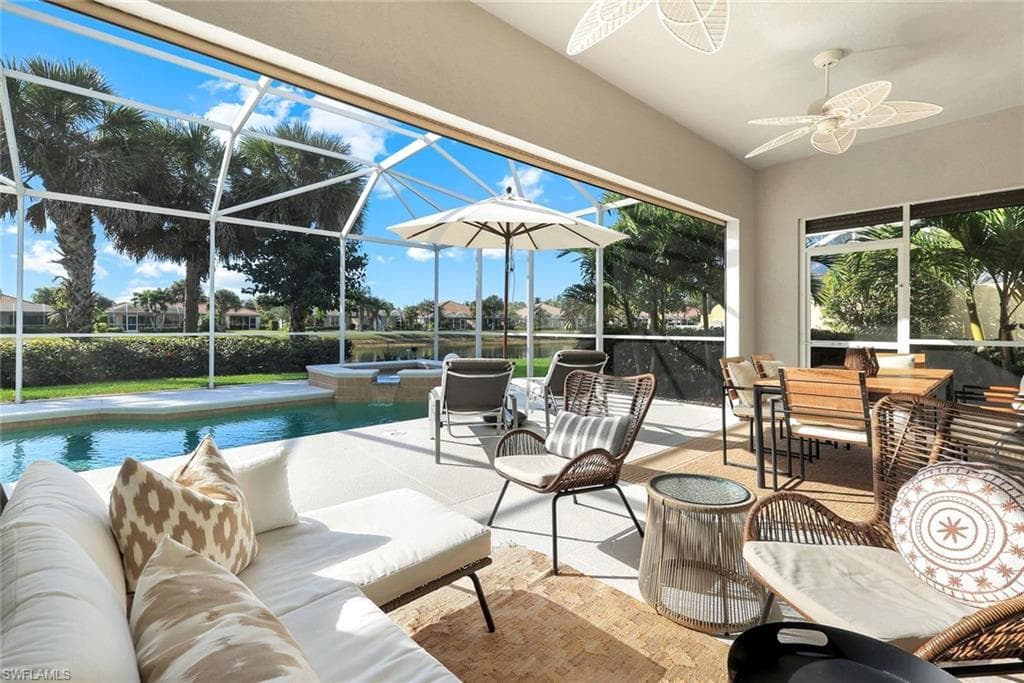 View of patio / terrace featuring a sunroom, a ceiling fan, glass enclosure, and a pool with connected hot tub