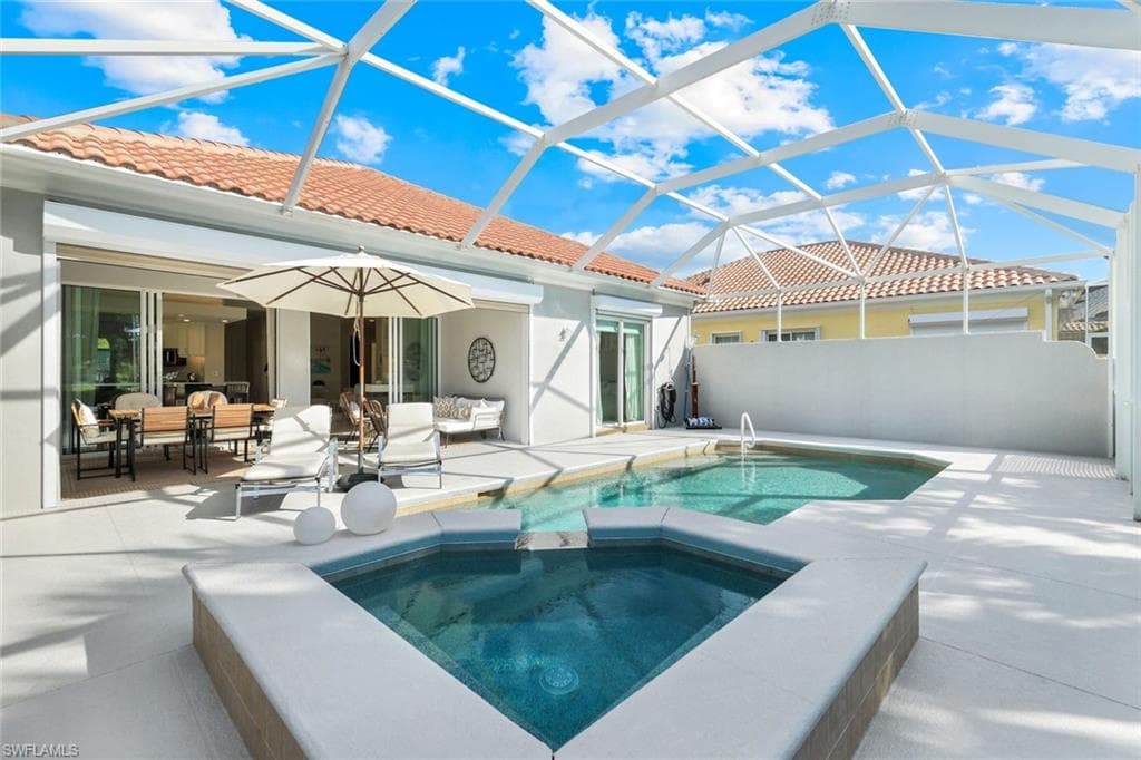 View of swimming pool featuring a sunroom, a patio area, glass enclosure, a pool with connected hot tub, and an outdoor living space