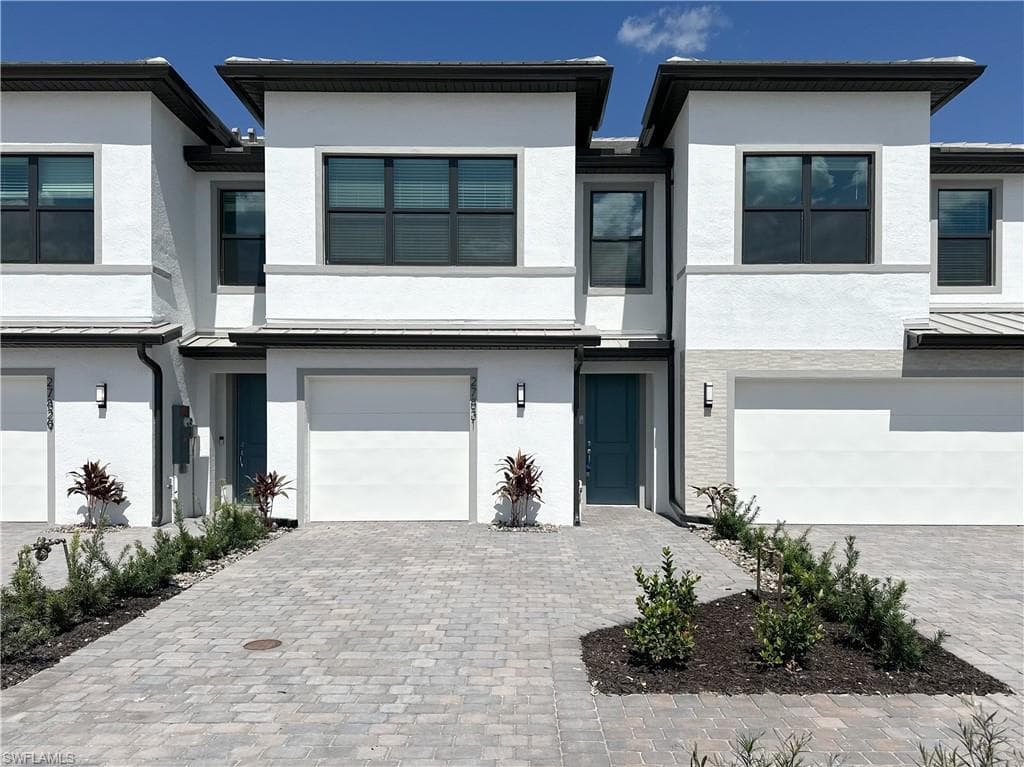 Contemporary home with stucco siding, a garage, and decorative driveway