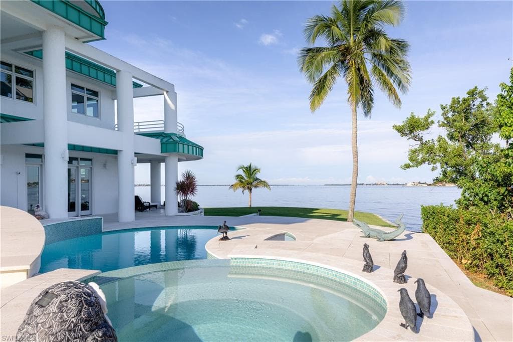 View of pool featuring a water view, a patio, french doors, and a pool with connected hot tub