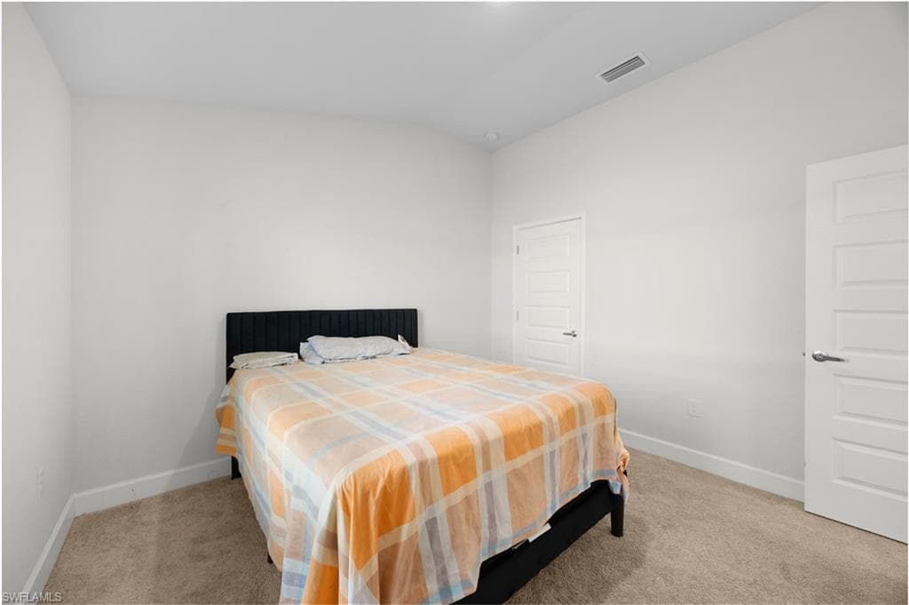 Bedroom with light colored carpet and lofted ceiling