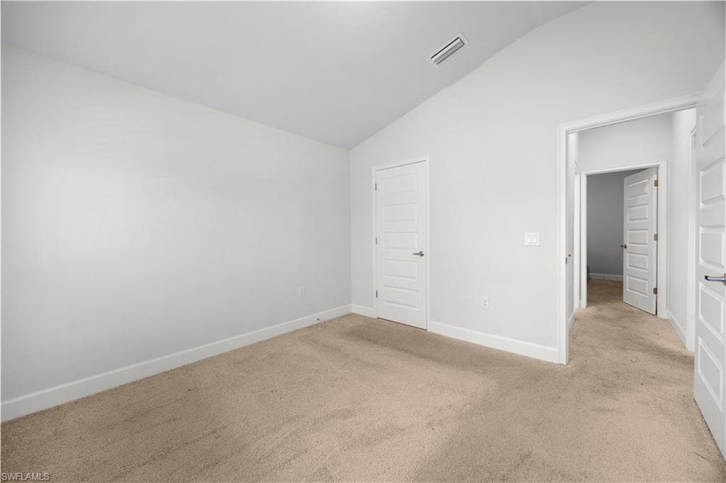 Unfurnished bedroom featuring lofted ceiling and carpet