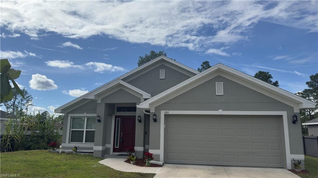 Ranch-style home with stucco siding, driveway, a front yard, and an attached garage