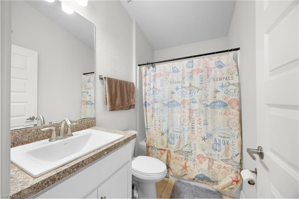 Bathroom with vanity, shower / bath combo, and light tile patterned floors