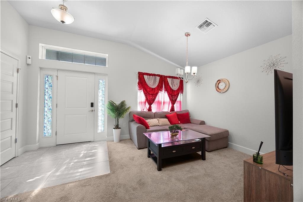 Living area featuring carpet, vaulted ceiling, and a chandelier