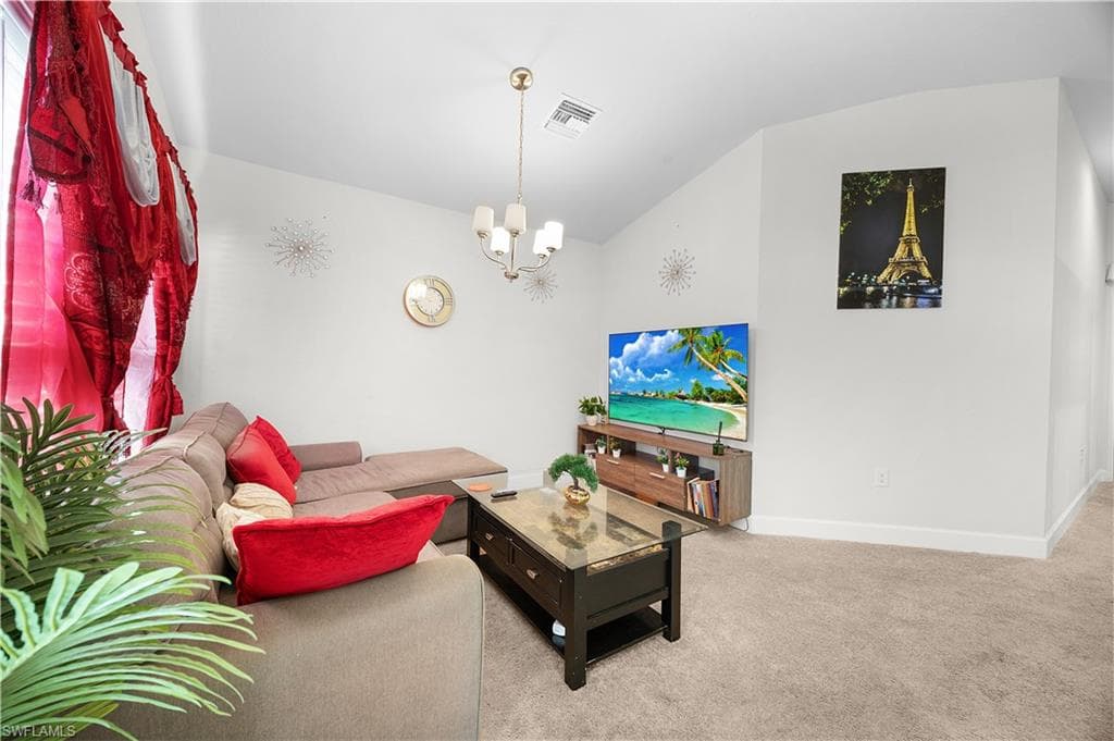 Carpeted living room with vaulted ceiling and a chandelier