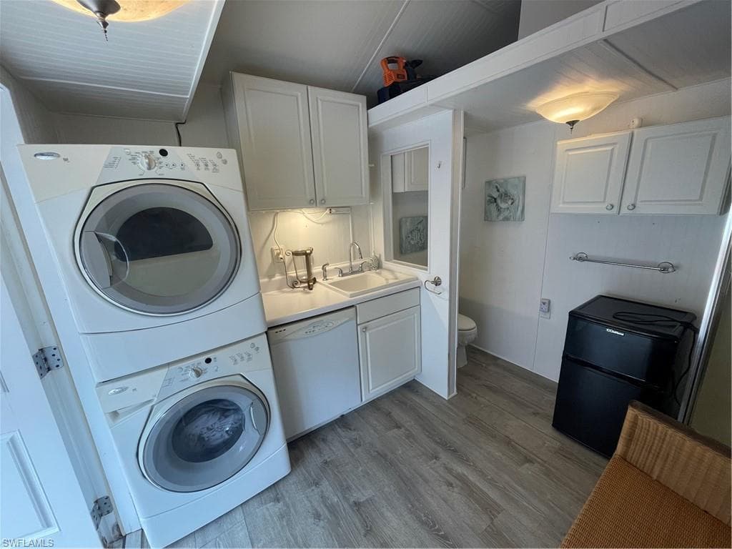 Laundry area featuring light wood-style flooring and stacked washing machine and dryer