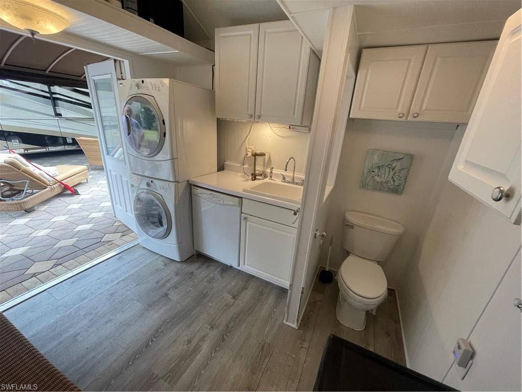 Bathroom with vanity, stacked washer / drying machine, and light wood-type flooring