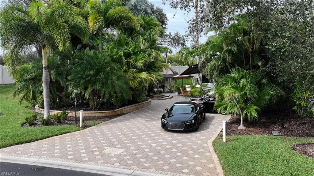 Surrounding community with a lawn, a patio, and decorative driveway