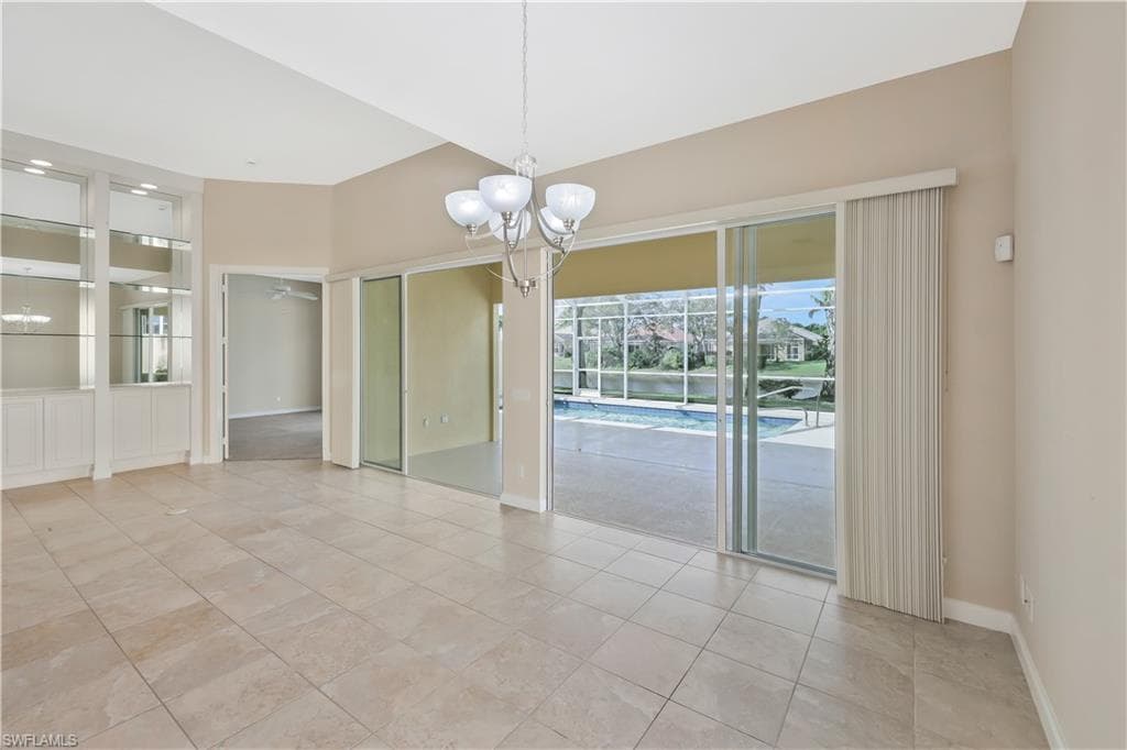 Unfurnished room with a chandelier and light tile patterned flooring