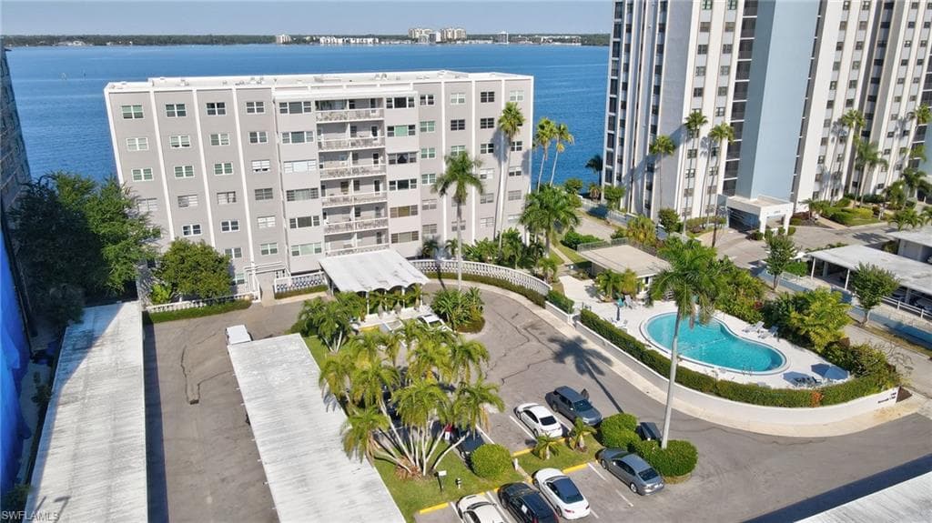 View of condo building featuring a water view, pool, BBQ area and carports