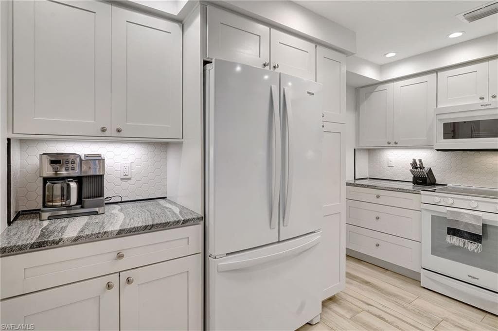 Kitchen featuring white appliances, tiled backsplash & recessed lighting