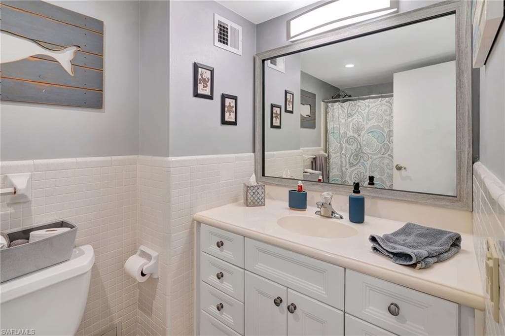 Full bathroom with vanity and tile walls