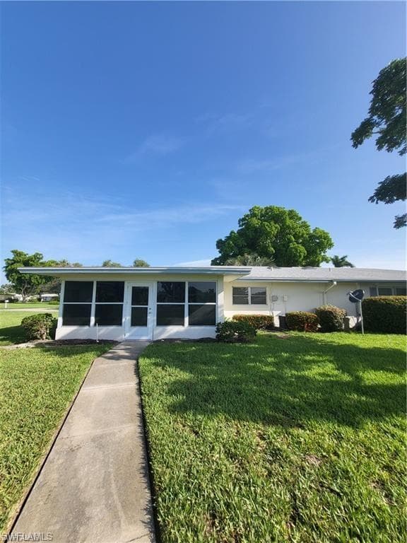 Back of house with a lawn and a sunroom