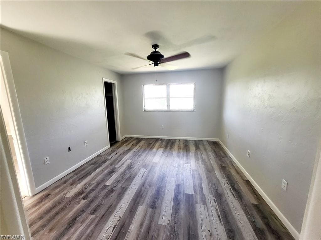 Empty room with dark wood-type flooring and a ceiling fan