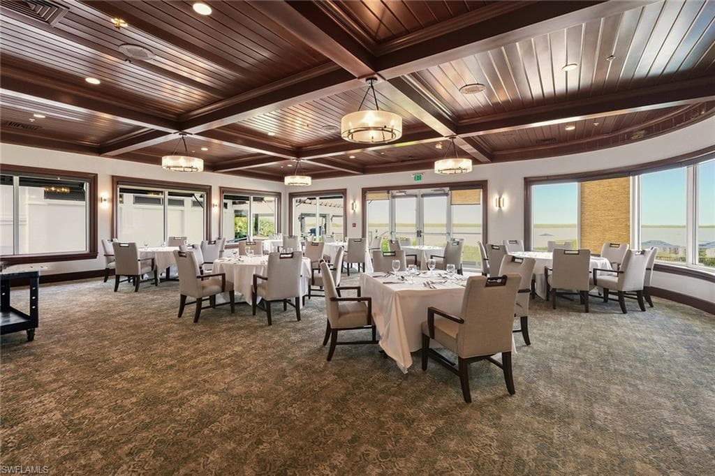 Dining area with a wood ceiling with exposed beams, dark colored carpet, healthy amount of natural light, and coffered ceiling