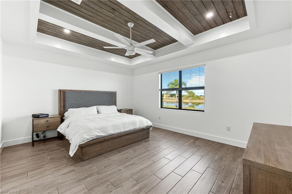 Bedroom featuring wood finish floors, a wooden ceiling with exposed beams, a tray ceiling, ceiling fan, and a water view