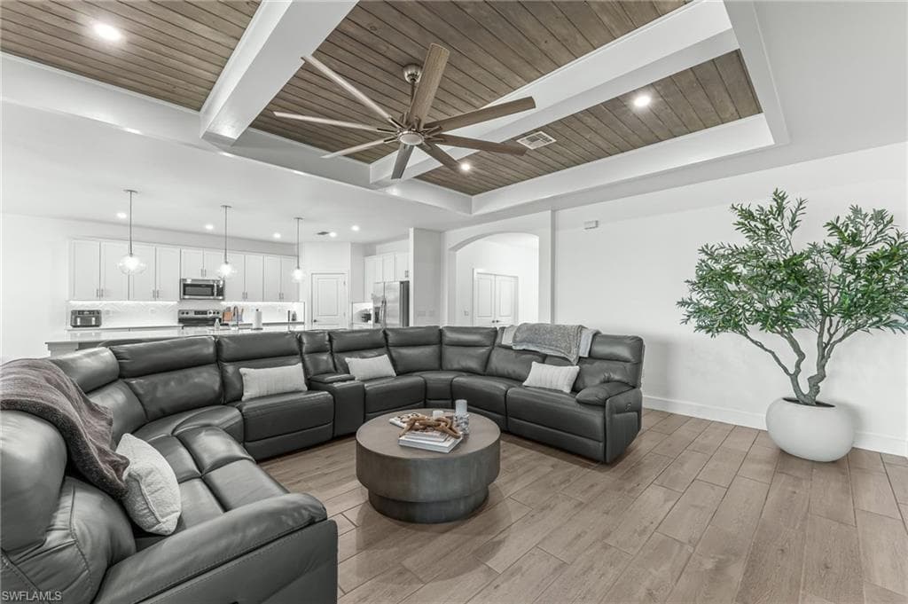 Living area with light wood finished floors, a wood ceiling with exposed beams, arched walkways, recessed lighting, and ceiling fan