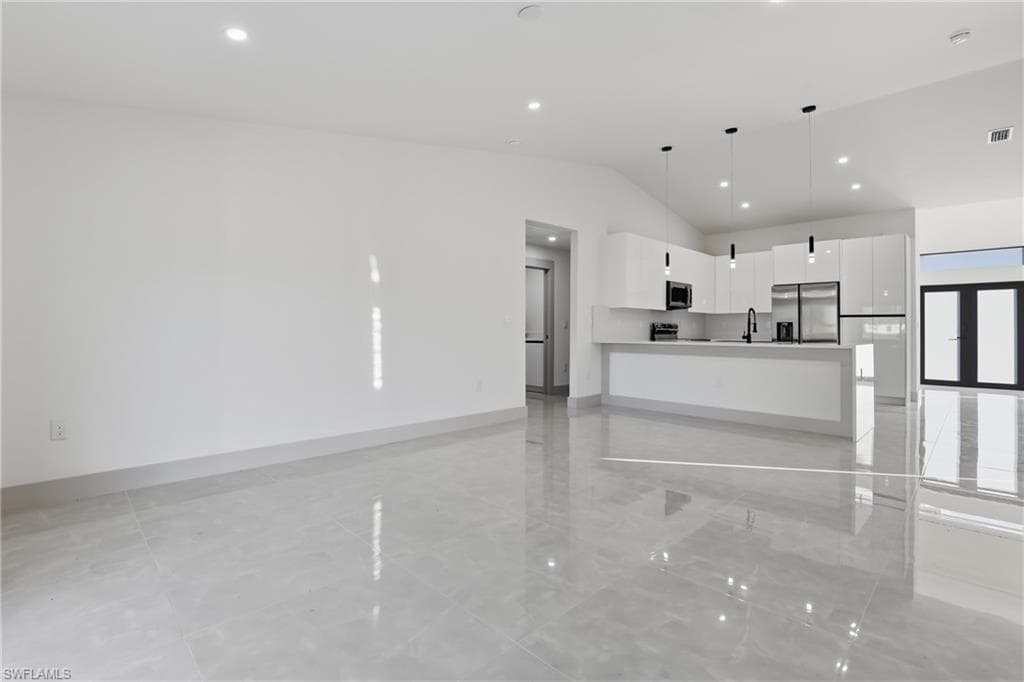 Unfurnished living room featuring vaulted ceiling and recessed lighting