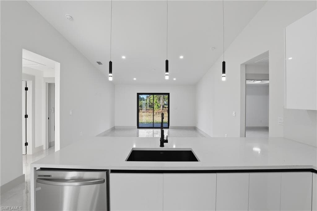 Kitchen featuring light stone countertops, white cabinets, stainless steel dishwasher, pendant lighting, and modern cabinets