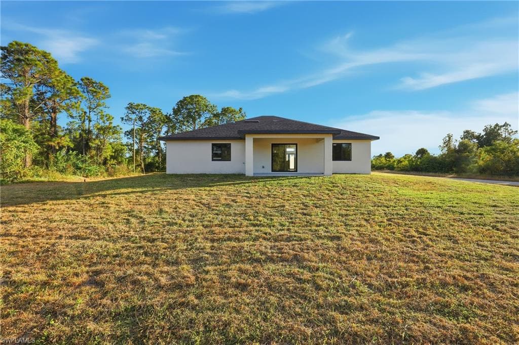 View of front of house with a patio, a front lawn, and stucco siding